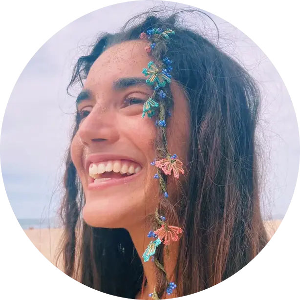 Circular picture of carolina smiling at the beach with petals in her hair